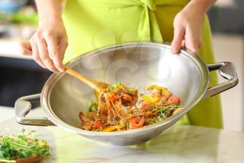 Woman cooking tasty Chinese noodles in wok�