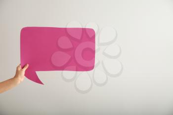 Female hand with blank speech bubble on light background�
