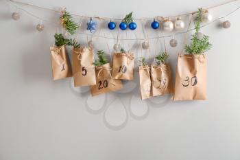 Paper bags with Christmas gifts and drawn numbers hanging on wall�