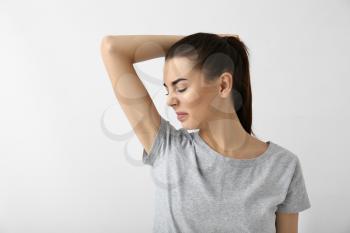 Beautiful young woman feeling smell of sweat on white background. Concept of using deodorant�