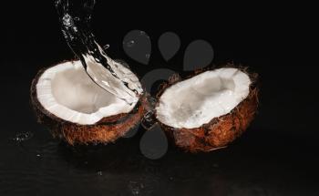 Ripe coconut and splash of water on dark background�