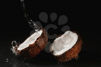 Ripe coconut and splash of water on dark background�