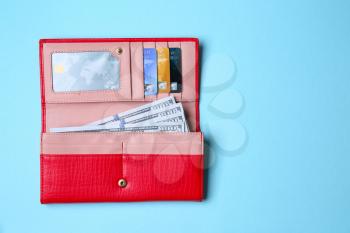 Wallet with money and credit cards on color background�