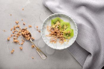 Tasty granola with yogurt in bowl on grey table�