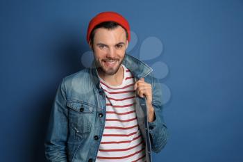Fashionable young man in jeans jacket on color background�