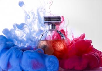 Bottle of perfume in color smoke on white background�