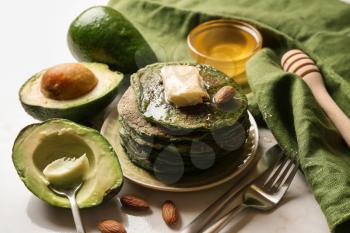 Tasty green pancakes with avocado on light table�
