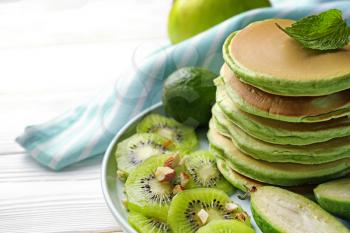 Tasty green pancakes on white wooden table�
