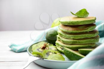 Tasty green pancakes on white wooden table�