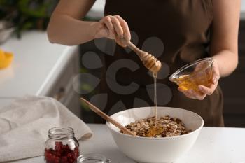 Woman making tasty granola bars in kitchen�