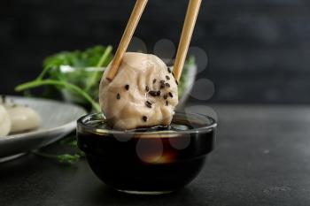Dipping of tasty Chinese dumpling into bowl with sauce�