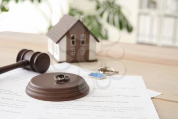 Rings with decree of divorce, judge gavel and key from house on table. Concept of dividing marital property�