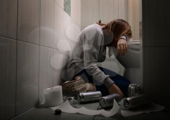Young vomiting woman near toilet bowl. Concept of alcoholism�