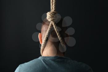 Man with noose around neck on dark background. Suicide awareness concept�