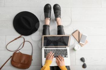 Female blogger with laptop sitting on floor�