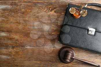 Judge's gavel, briefcase and scales of justice on wooden background�