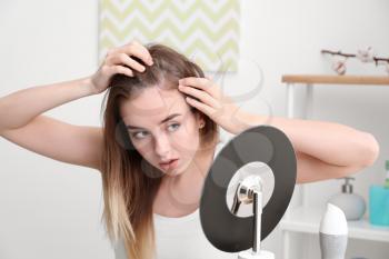 Woman with hair loss problem looking in mirror�
