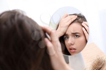 Woman with hair loss problem looking in mirror�