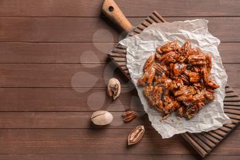 Tasty candied pecan nuts on wooden table�