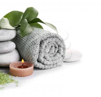 Beautiful spa composition with stones, towel and candle on white background�