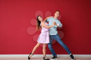 Young couple dancing near color wall�
