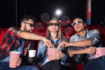 Guys eating popcorn from their friend's bucket in cinema�