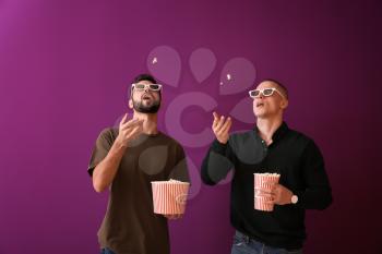 Guys catching popcorn with their mouths on color background�