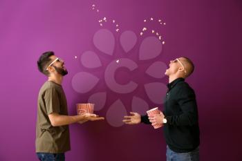 Guys catching popcorn with their mouths on color background�