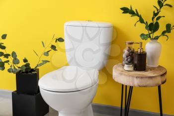 Modern ceramic toilet bowl near color wall in restroom�