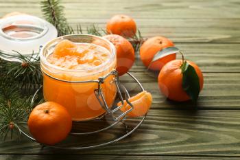 Jar of tasty tangerine jam on wooden table�