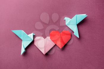 Origami birds and hearts on color background�