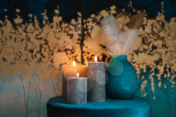 Beautiful burning candles with decor on pouf�