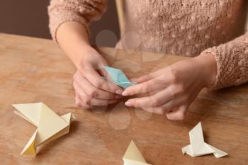 Young woman with origami bird at table, closeup�