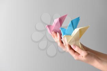 Female hands with origami birds on light background�