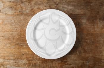 Empty ceramic plate on wooden background�