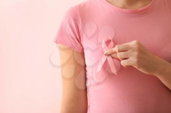Woman with pink ribbon on color background. Breast cancer awareness concept�