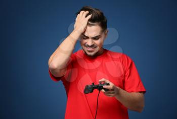 Young man after losing video game on color background�