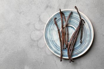 Plate with aromatic vanilla sticks on grey background�