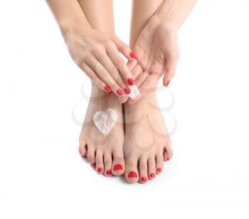 Young woman with beautiful pedicure applying cream on white background�
