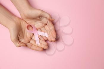 Female hands with pink ribbon on color background. Breast cancer awareness concept�