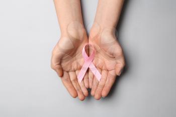 Female hands with pink ribbon on light background. Breast cancer awareness concept�