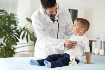 Male doctor working with cute little boy in clinic�
