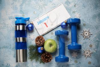 Christmas composition with calendar, bottle of water and dumbbells on color background�