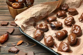 Sweet dried dates covered with chocolate on baking tray�