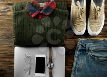 Set of stylish male clothes, accessories and laptop on wooden background�
