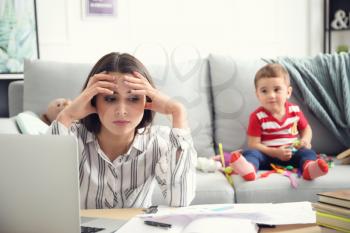 Tired mother with her son working at home�