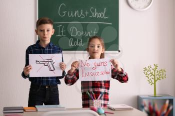 Cute little children with agitation posters in classroom. Concept of school shooting�