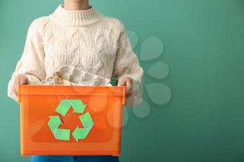 Woman holding box with trash on color background. Recycle concept�