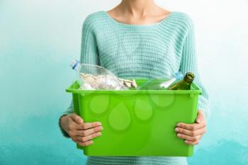 Woman holding box with trash on color background. Recycle concept�
