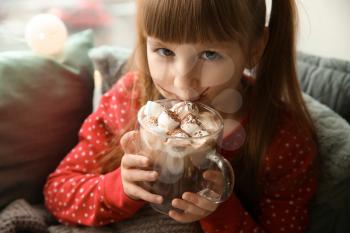 Cute little girl drinking hot chocolate at home�